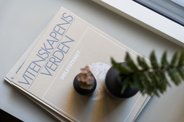Un magazine intitulé « Wienskapers Verden » est posé sur un rebord de fenêtre, à côté d’une plante en pot.