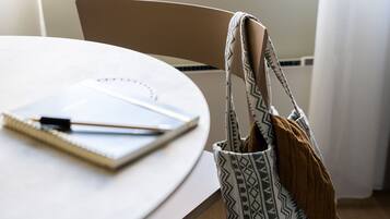 Una mesa redonda con un cuaderno, un bolígrafo y una bolsa estampada.