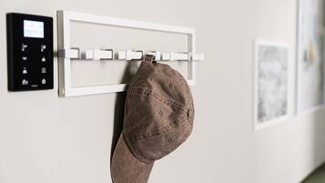 Un gancho para abrigos en la pared con un gorro colgado, un panel de control y un cuadro enmarcado.