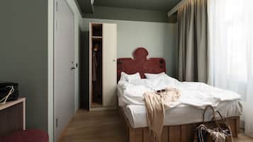 A bedroom with a wooden bed, a wardrobe, a small seating area, and a closet.