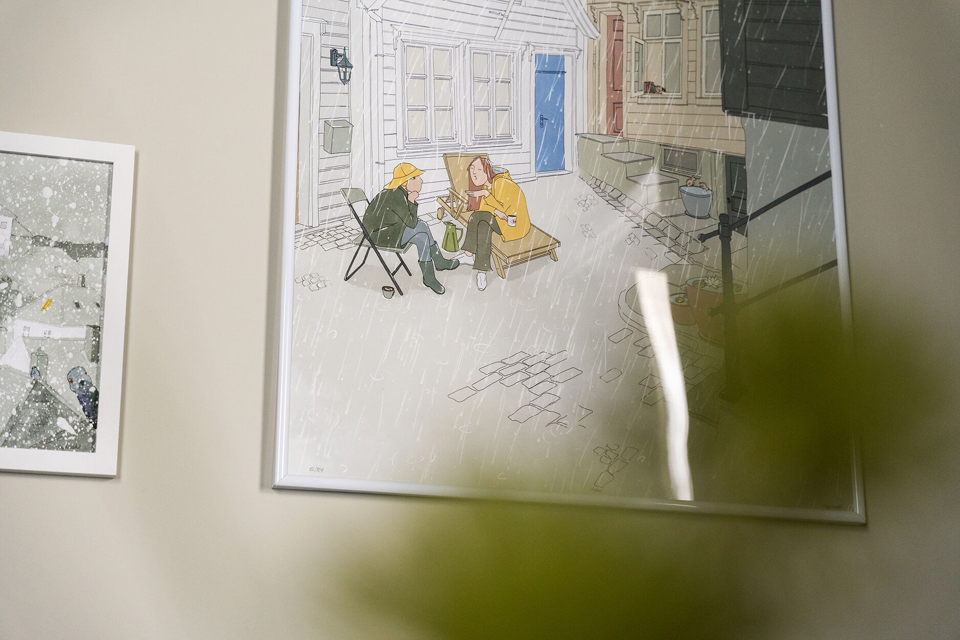 Une illustration encadrée représentant deux personnes assises sur un banc devant une maison, avec une porte bleue et une fenêtre blanche visibles.