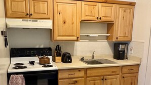 Une cuisine avec des meubles de rangement en bois, une cuisinière, un évier et une machine à café.
