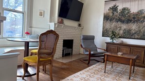 Un salon avec une cheminée, un téléviseur et un grand tableau.