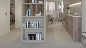 A modern kitchen with a central island, a built-in bookshelf, and a dining area with chairs.