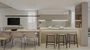 A modern kitchen with a central island, bar stools, a dining area with chairs, and a TV mounted on the wall.