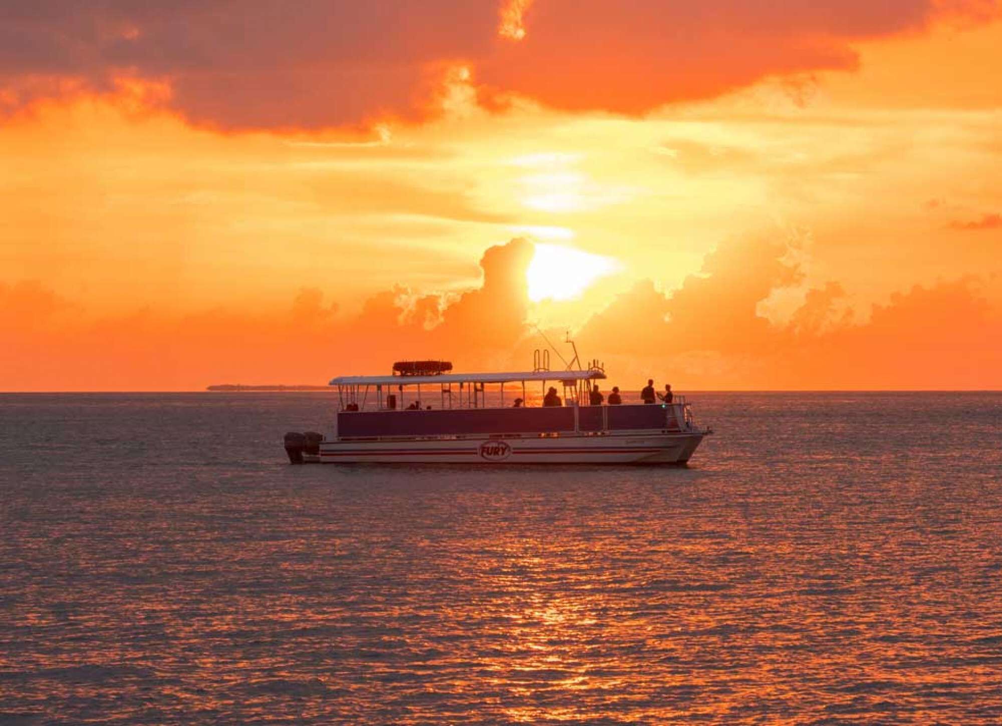 Ein Boot mit Passagieren auf ruhiger See im Sonnenuntergang.