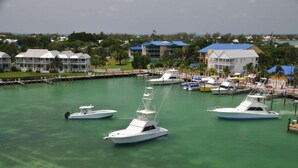 A marina with several boats docked, surrounded by buildings with blue roofs and a clear view of the water. - Ocean Bliss | Nature Center. Two Bedroom Private Villa (Duck Key)