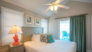 A bedroom with a bed, a nightstand, a ceiling fan, and a view of the outside. - Ocean Bliss | Nature Center. Two Bedroom Private Villa (Duck Key)