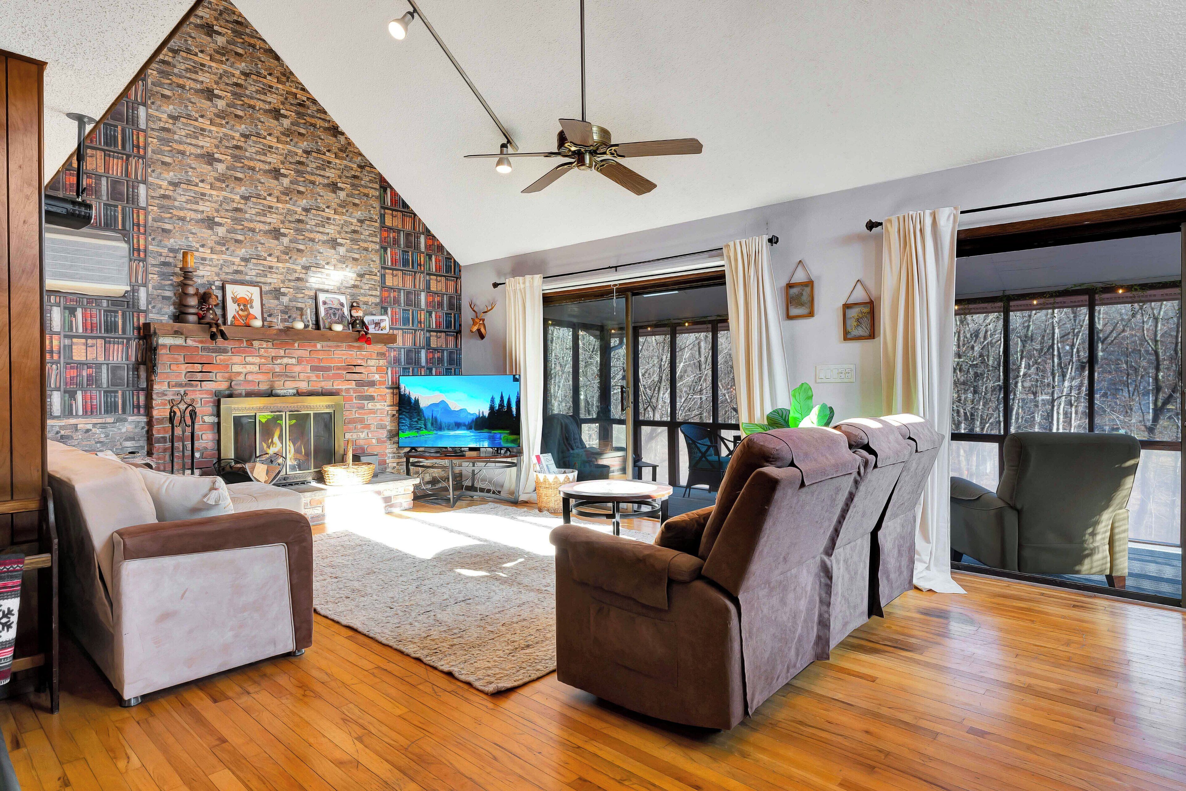 Una sala de estar acogedora con chimenea, televisor y un amplio ventanal con vistas a un paisaje nevado.