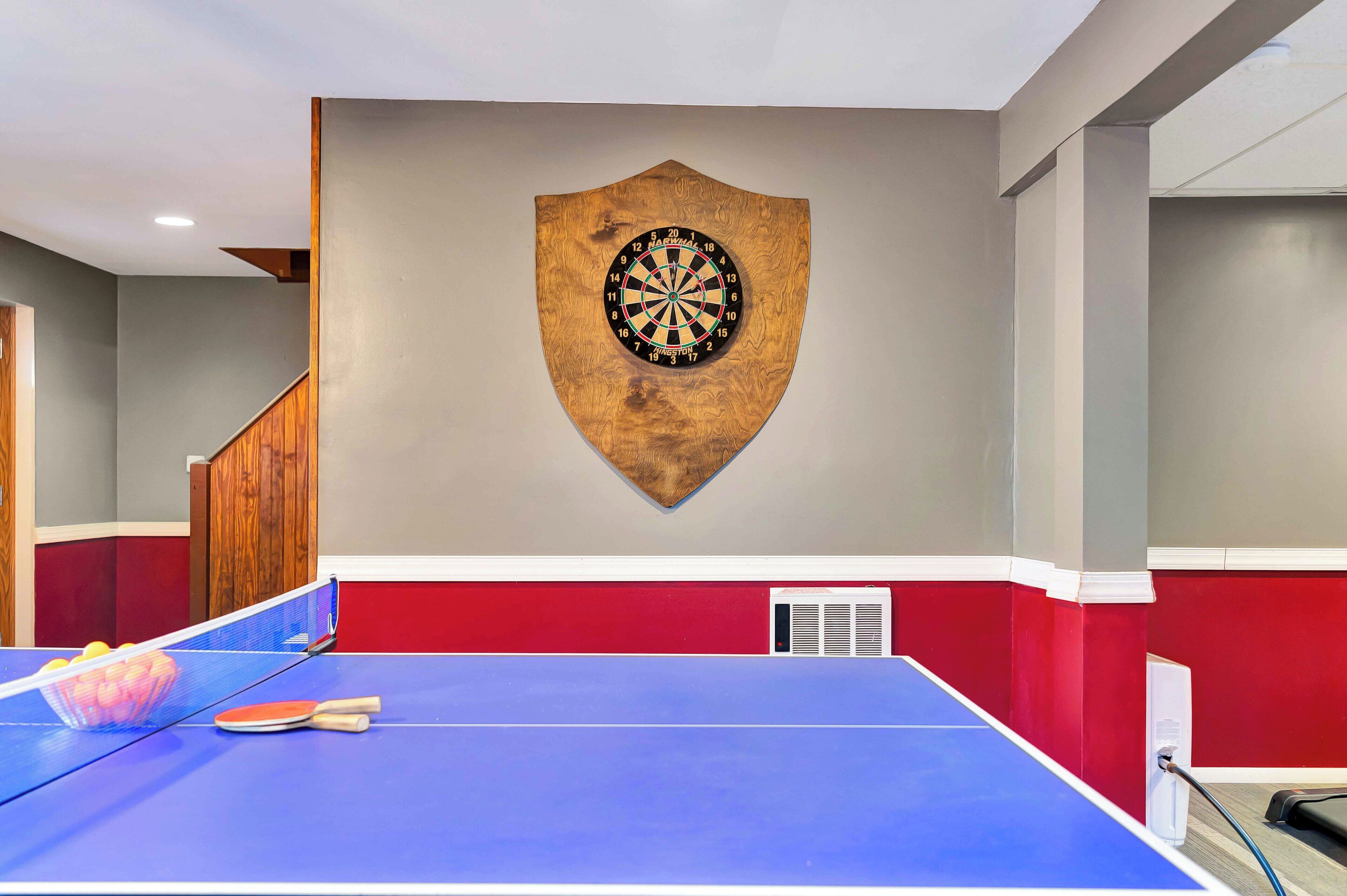 A ping pong table with a dartboard mounted on the wall.