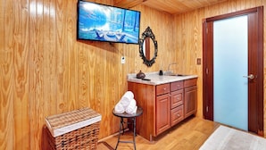 Una habitación con paneles de madera, un televisor, un lavabo y una puerta.