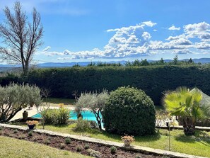 A pool surrounded by various plants and trees, with a view of distant mountains and a clear sky. - Villa Saint Donat, swimming pool, relaxation (Lorgues)