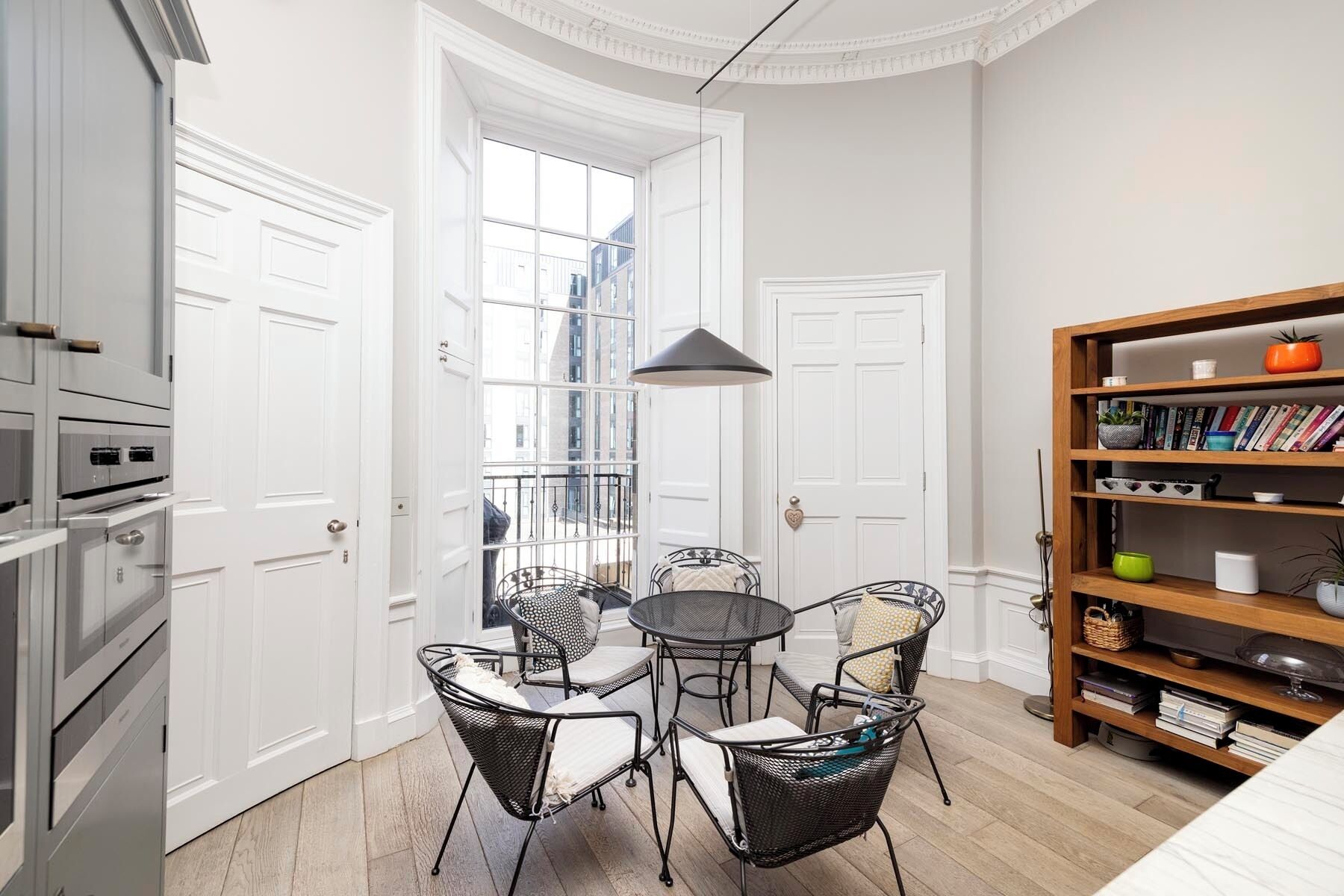 A compact living space with a dining area, kitchenette, and a bookshelf.
