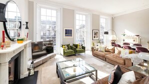 A spacious living room with a fireplace, large windows, and a modern sofa set. - Stunning 4 bedroom Townhouse in central Edinburgh with garden & private parking (Edinburgh)