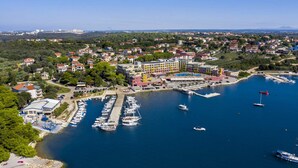 Vista aérea de un pueblo costero con un puerto deportivo, edificios coloridos y barcos.