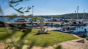 Un puerto deportivo con barcos amarrados, una estatua y una furgoneta en el muelle.