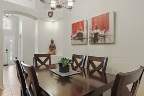 A dining room with a wooden table, chairs, a potted plant, and two paintings on the wall. - ⭐⭐Beautiful 4 Bed 3 Bath Villa with Stunning Lake View from Private Pool Deck⭐⭐ (Clermont)