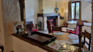 Een knusse woonkamer met een open haard, een houten tafel en een comfortabele zithoek.