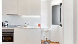 A modern kitchen with white cabinets, a stainless steel sink, and a Siemens oven. - GuestReady - Old City Design - Faces (Porto)