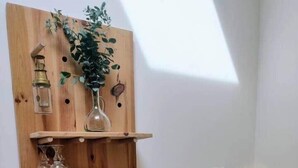 A bathroom with a wooden vertical shelf unit holding various toiletries, a potted plant, and a marble sculpture. - Studio Mandavi - Vineyards & Forest (Loupes)