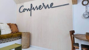 A room with a wooden wall, a metal sign reading 'Conférence,' a wooden chair, and a small table. - Studio Mandavi - Vineyards & Forest (Loupes)