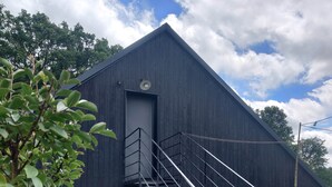 A building with a staircase leading to a door, surrounded by gravel and plants. - Studio Mandavi - Vineyards & Forest (Loupes)
