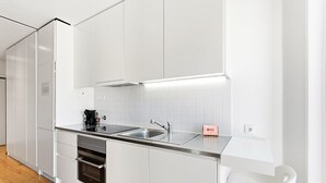 Ett modernt kök med vita skåp, en diskho i rostfritt stål och en inbyggd ugn.