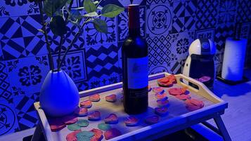 A kitchen counter with a bottle of wine, a vase with roses, and a tray with candles.