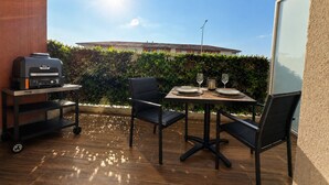 An outdoor patio with a grill, two chairs, a table set for two, and a view of a building in the background. - Suite Eden Spa, Appart’hôtel bien être , Patio (Avion)