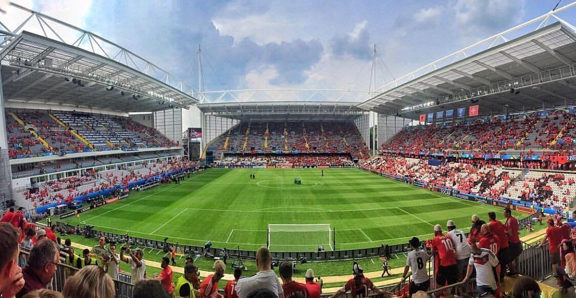 Un estadio con asientos escalonados, un campo central y una gran multitud.