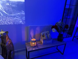Una habitación moderna con un sofá, una mesita con un farolillo y una escultura decorativa.