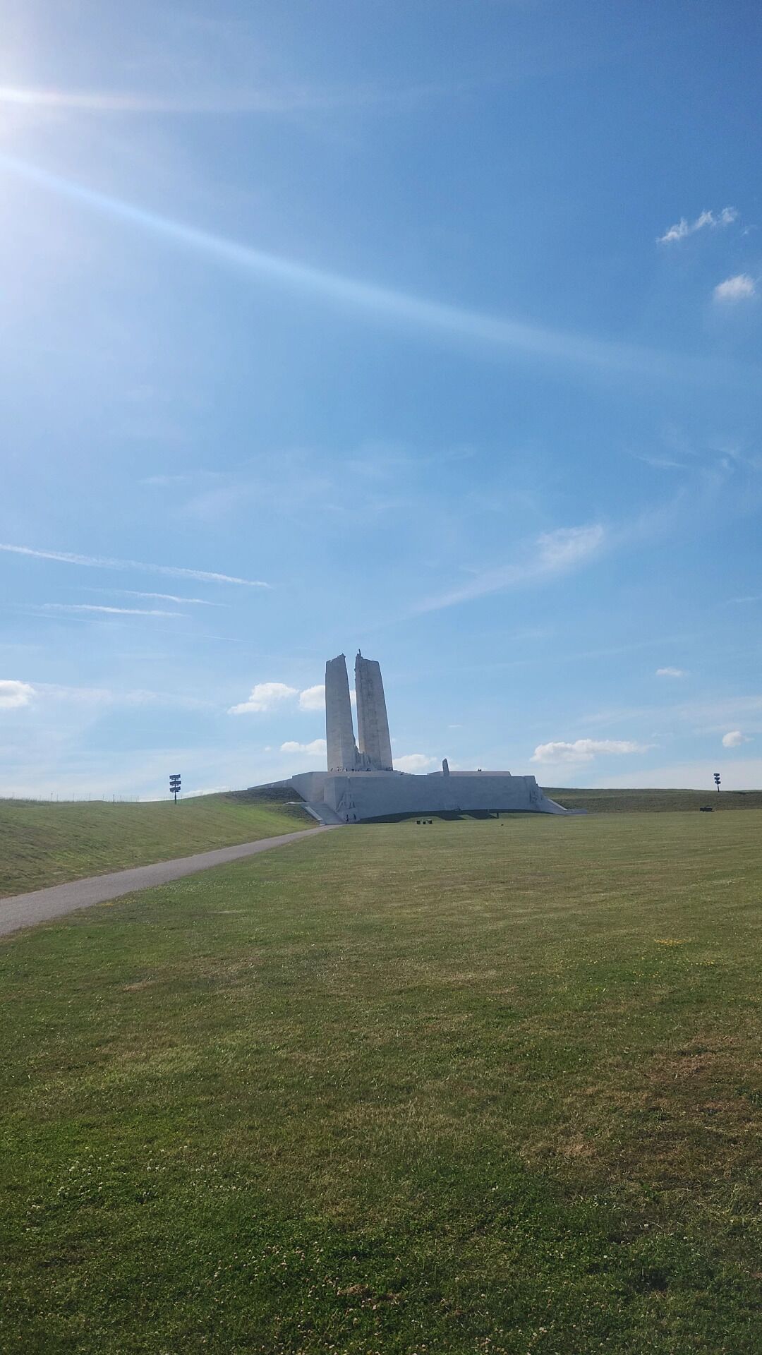 Un vaste champ herbeux à perte de vue, avec un monument imposant qui se détache à l’horizon.