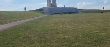 Un vaste champ herbeux à perte de vue, avec un monument imposant qui se détache à l’horizon.