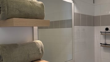 A bathroom with a white sink, a mirror, and two towel racks.