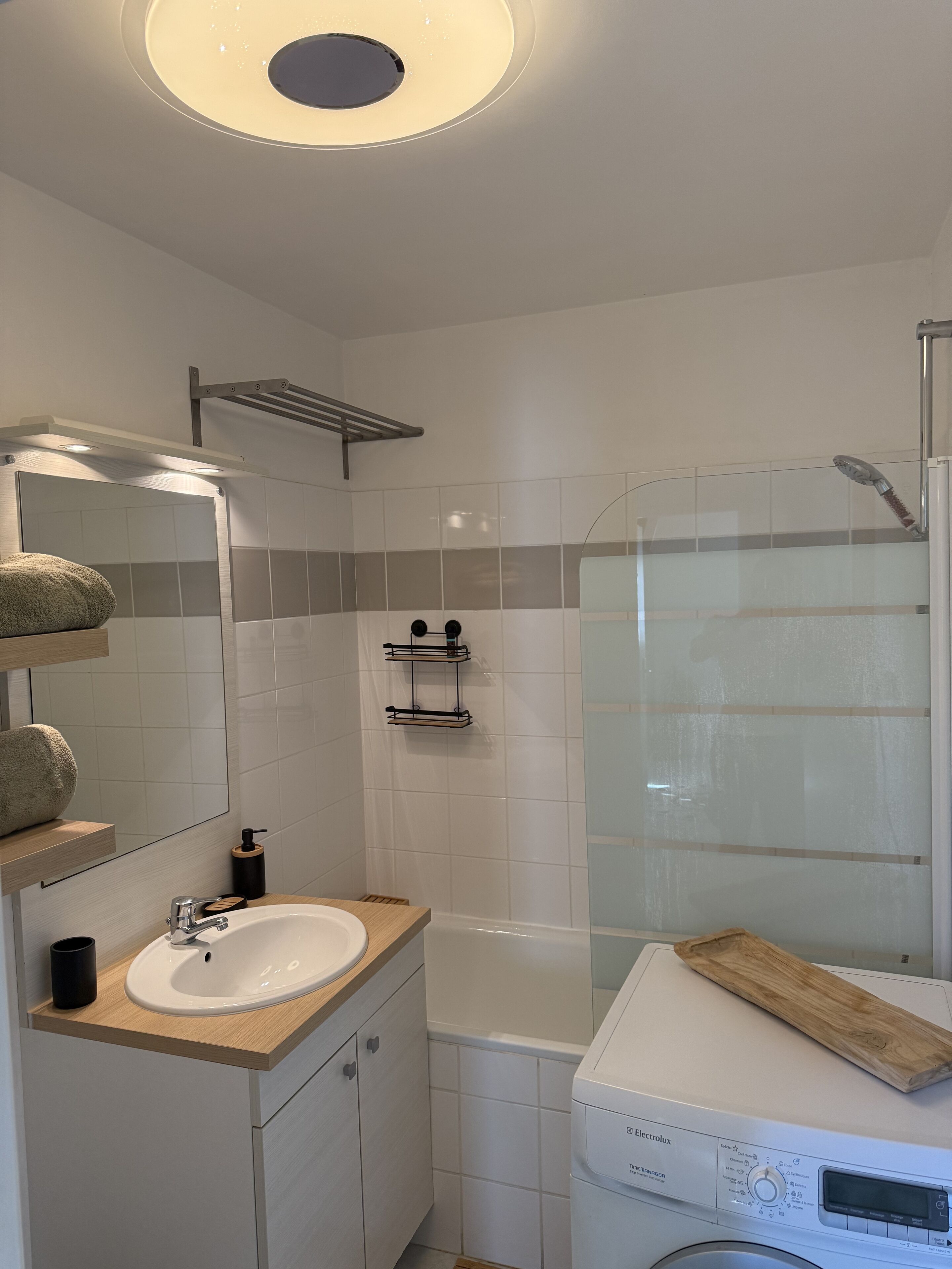 A modern bathroom with a white sink, mirror, and shower.