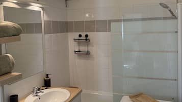 Un bany modern amb un lavabo, un mirall i una dutxa de color blanc.
