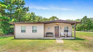 Une maison de plain-pied avec un porche à l’avant, un petit garage attenant et une boîte aux lettres.