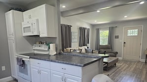 A modern kitchen with white cabinetry, a built-in microwave, and a grey countertop.