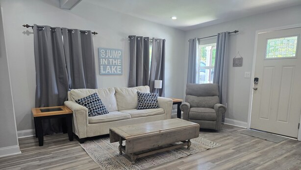 A living room with a sofa, armchair, coffee table, and a rug.