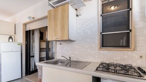 Eine kompakte Küche mit einer eingebauten Gaskochplatte, einem Spülbecken und einem weißen Kühlschrank.