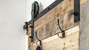 A wooden wall with a built-in coat rack and hooks. - Farm Stay, 1-bedroom custom built shipping container on the river. (Ovando)