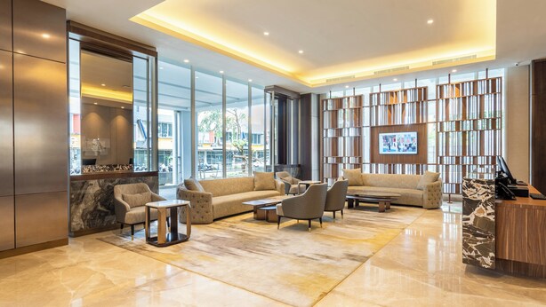 Een moderne lobby met een bank, fauteuils, een receptiebalie en een boekenkast.