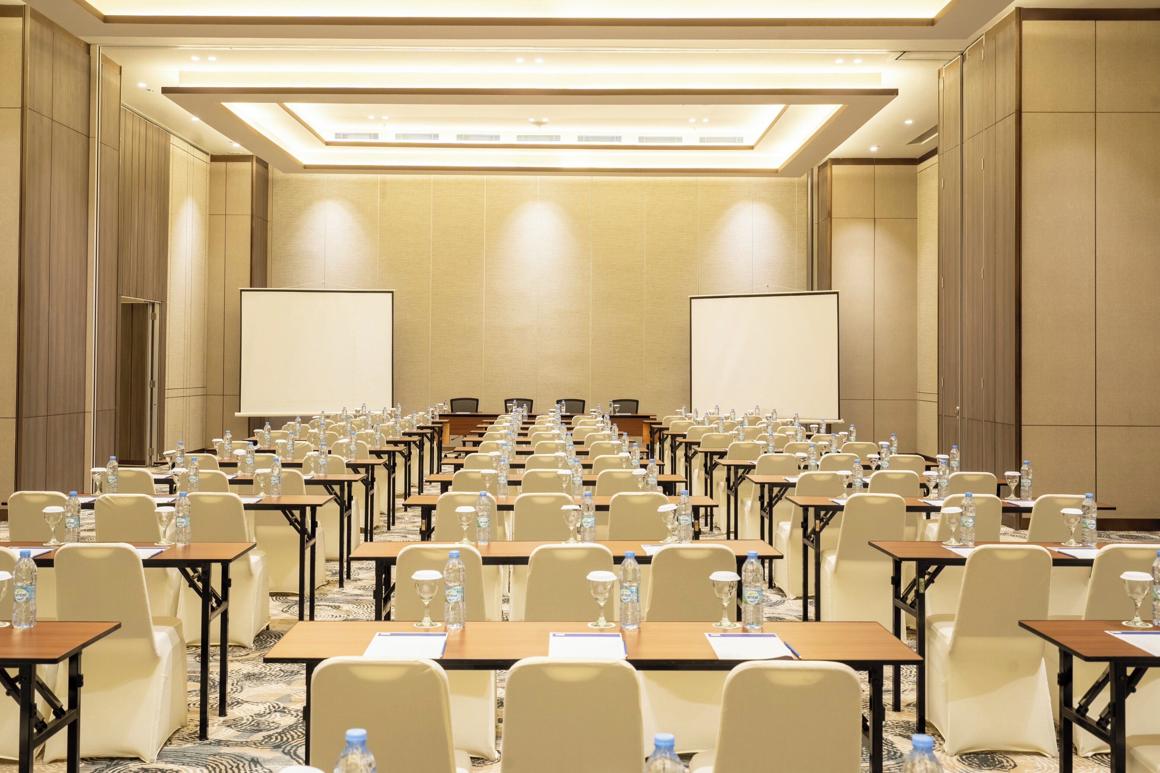 A conference room with rows of tables, chairs, and water bottles.
