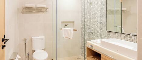 A modern bathroom with a glass-enclosed shower, a white toilet, and a large sink with a mirror above it.