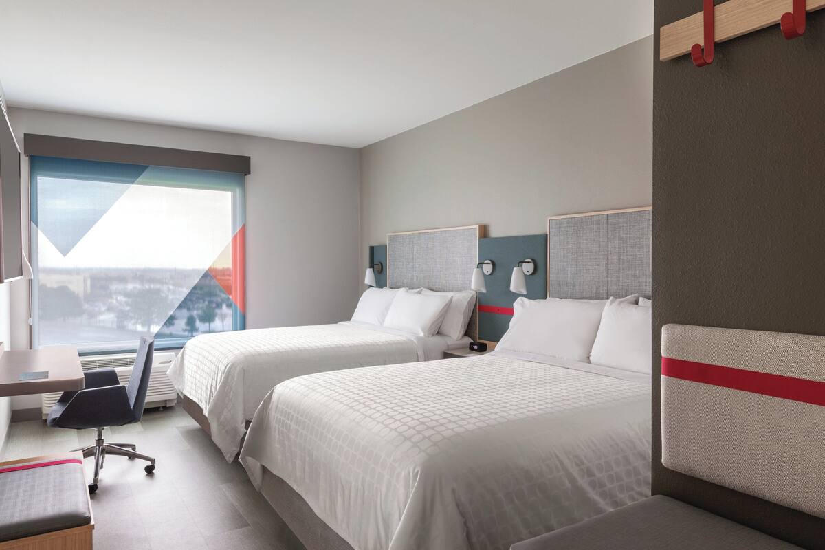 Una habitación de hotel con dos camas, un escritorio y una silla.
