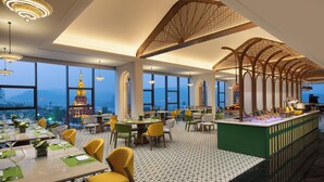 A modern restaurant with high ceilings, large windows, and a view of a mountain. Tables are set with green placemats and yellow chairs. - voco Xishuangbanna Gaozhuang by IHG (Xishuangbanna Dai)