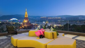 A rooftop seating area with a view of a cityscape, including a prominent building with a spire. - voco Xishuangbanna Gaozhuang by IHG (Xishuangbanna Dai)