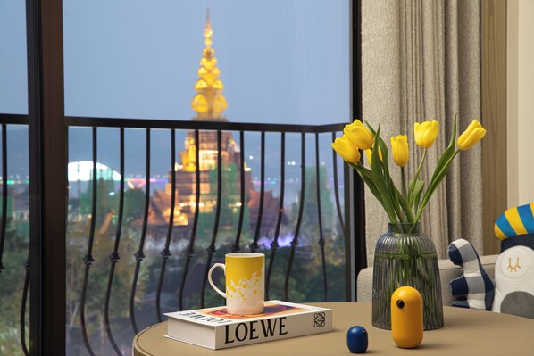 A table with a book titled "LOEWE," a mug, a vase with yellow tulips, and a plush toy.