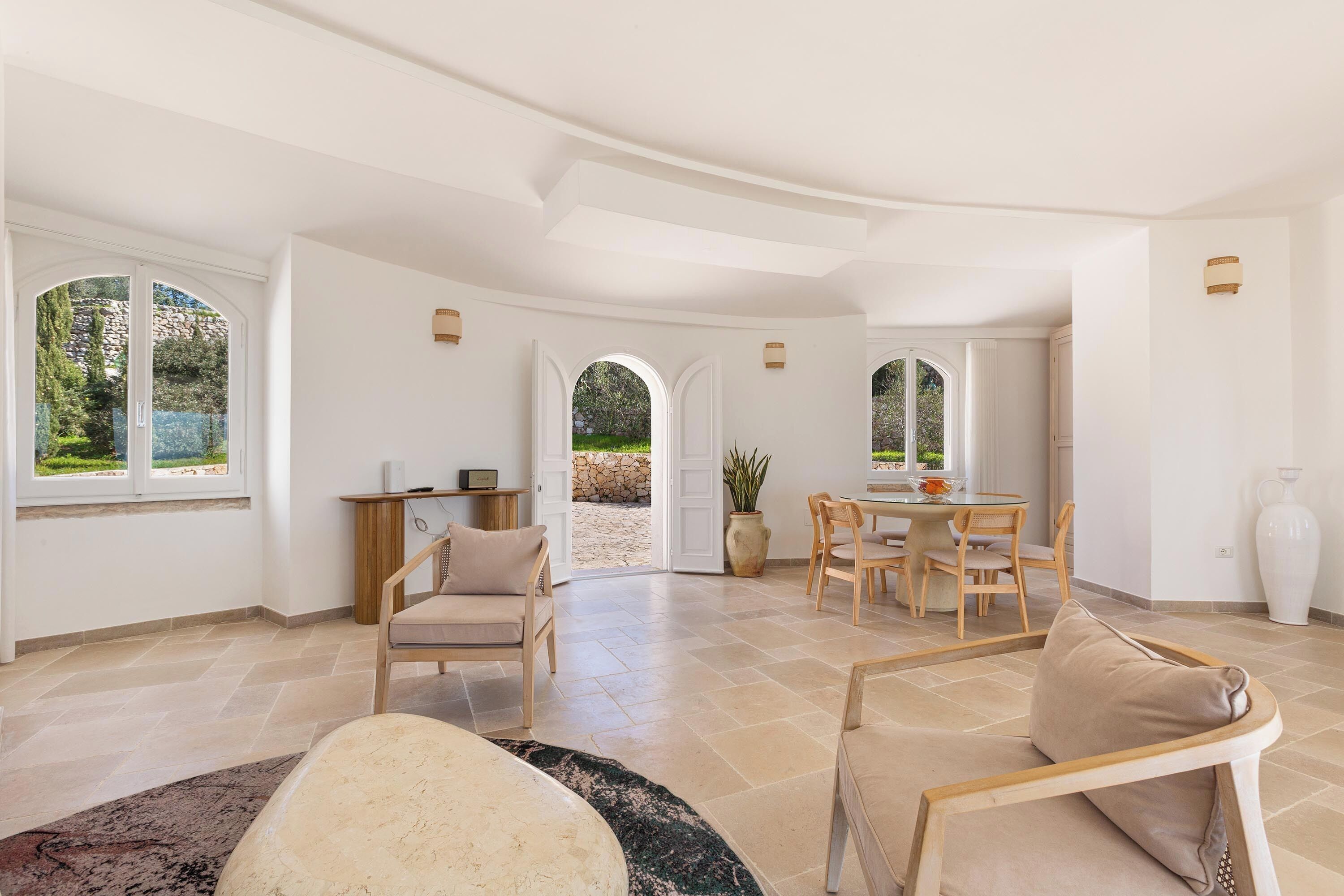 A spacious living area with a dining table, multiple chairs, and a large window offering a view of the outdoors.