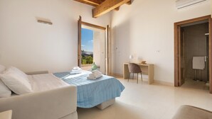 Ein Schlafzimmer mit einem Bett, einem Schreibtisch, einem Stuhl und einem durch eine offene Tür einsehbaren Badezimmer.